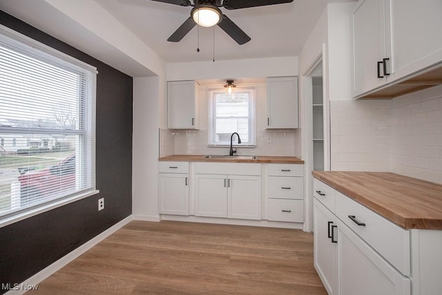 kitchen with wood counters, tasteful backsplash, sink, light hardwood / wood-style flooring, and white cabinetry