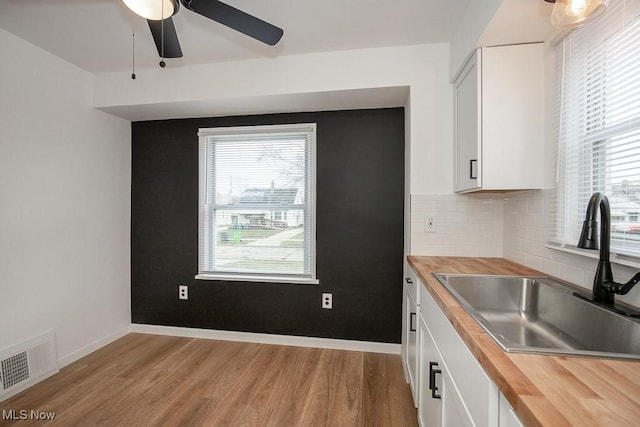 kitchen featuring a wealth of natural light, white cabinetry, sink, and butcher block counters