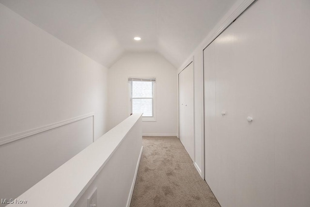 hall with light colored carpet and vaulted ceiling