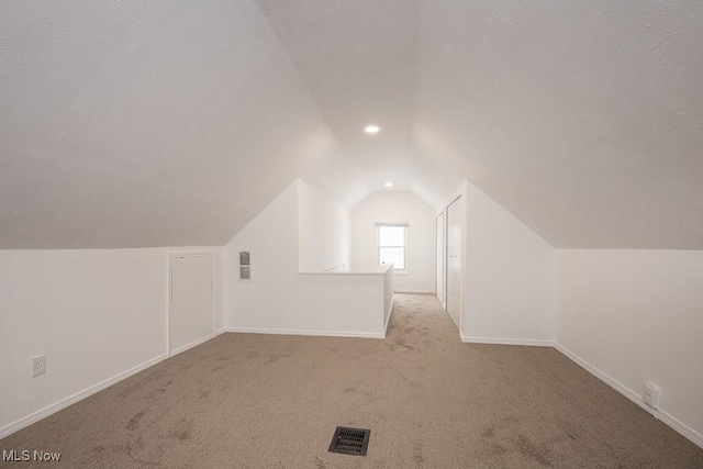 bonus room featuring light carpet and vaulted ceiling