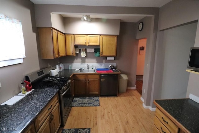 kitchen with stainless steel gas range oven, sink, black dishwasher, and light hardwood / wood-style flooring