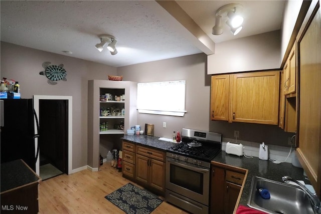 kitchen featuring black refrigerator, gas range, a textured ceiling, sink, and light hardwood / wood-style flooring