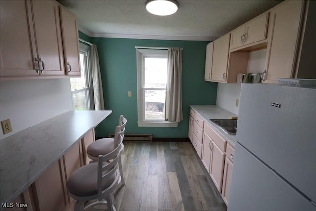 kitchen featuring sink, dark wood-type flooring, white fridge, a breakfast bar area, and ornamental molding