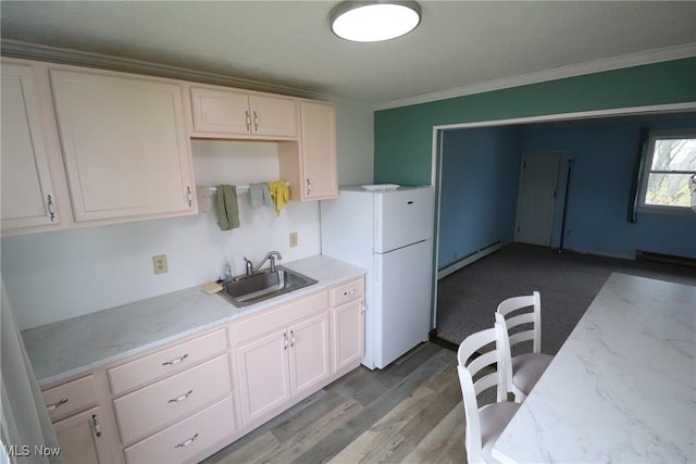 kitchen featuring a baseboard heating unit, sink, hardwood / wood-style flooring, ornamental molding, and white fridge