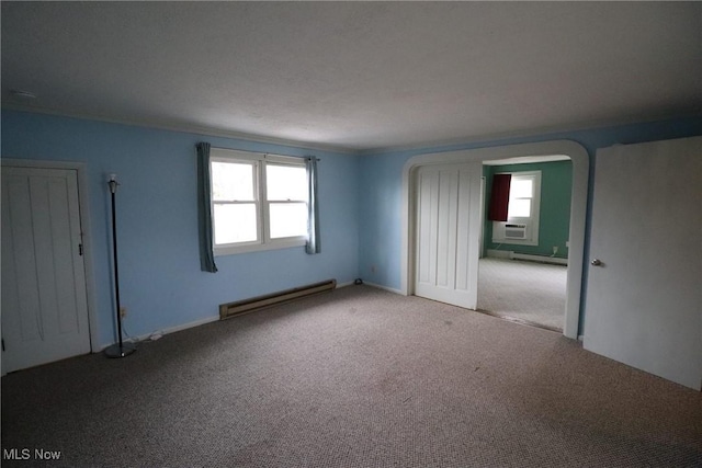 carpeted spare room with cooling unit, a healthy amount of sunlight, and a baseboard heating unit