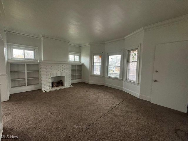 unfurnished living room with dark colored carpet, a fireplace, crown molding, and a wealth of natural light