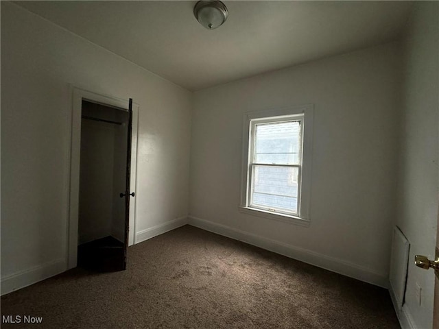 unfurnished bedroom featuring dark carpet and a closet