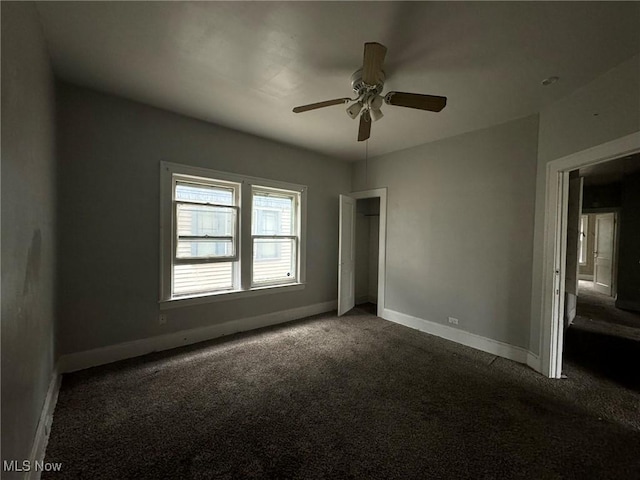 unfurnished bedroom with ceiling fan and dark carpet