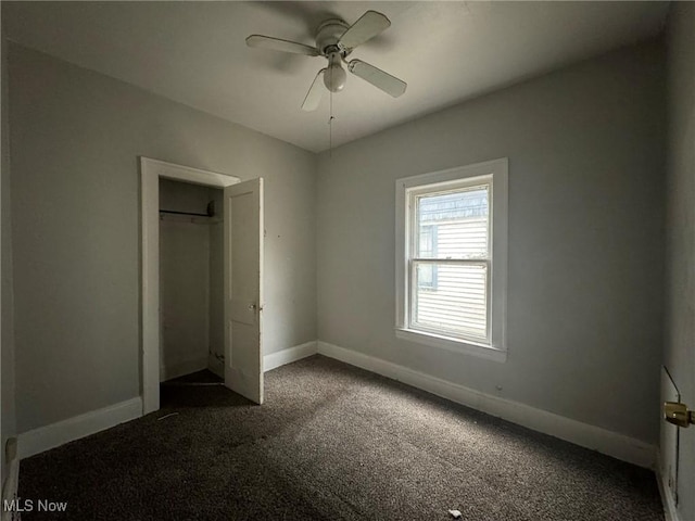 unfurnished bedroom with ceiling fan, a closet, and dark colored carpet