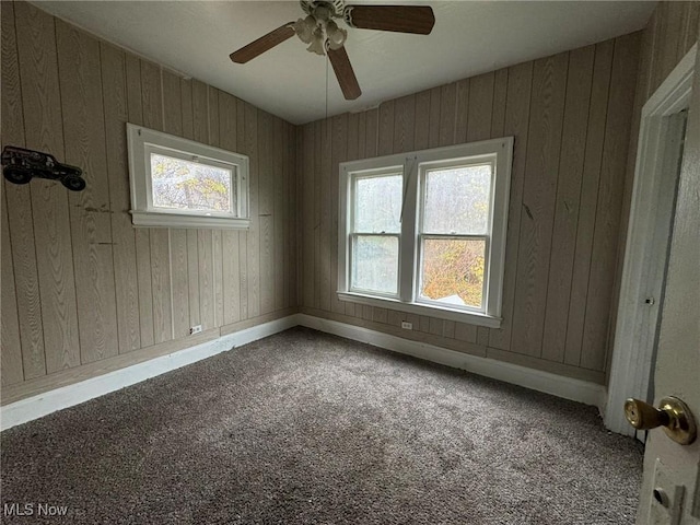 spare room featuring carpet flooring, ceiling fan, and wooden walls