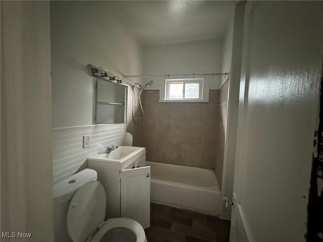 full bathroom featuring vanity, toilet, tiled shower / bath, and tile walls