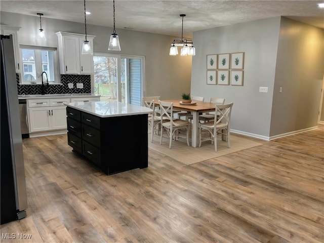 kitchen featuring white cabinetry, a center island, pendant lighting, and light hardwood / wood-style flooring