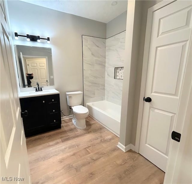 full bathroom with vanity, hardwood / wood-style flooring, toilet, and tiled shower / bath combo