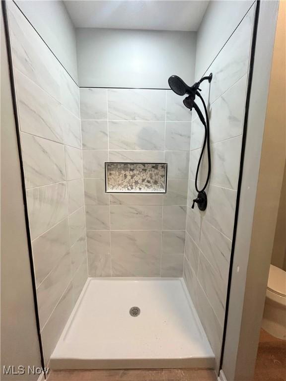 bathroom with toilet and tiled shower