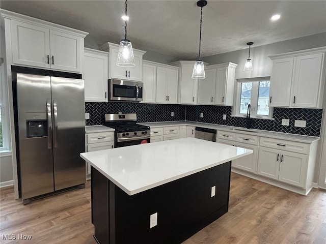 kitchen with pendant lighting, a center island, wood-type flooring, and appliances with stainless steel finishes