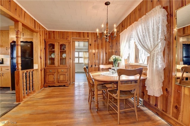 dining room featuring light hardwood / wood-style floors, an inviting chandelier, wooden walls, and crown molding