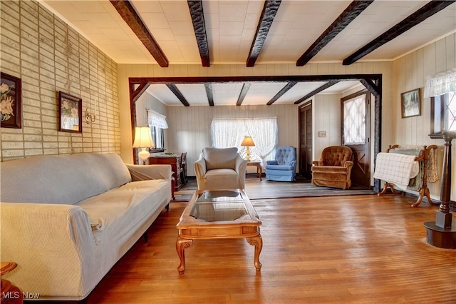 living room featuring hardwood / wood-style flooring, a healthy amount of sunlight, beam ceiling, and wooden walls