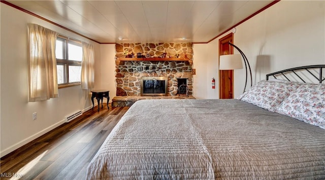 unfurnished bedroom featuring a stone fireplace, dark wood-type flooring, and ornamental molding