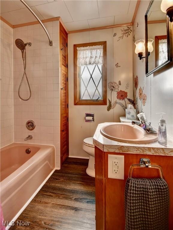 full bathroom with tiled shower / bath combo, crown molding, toilet, vanity, and hardwood / wood-style flooring