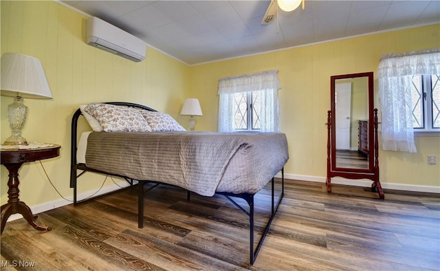 bedroom featuring hardwood / wood-style flooring, ceiling fan, ornamental molding, and a wall unit AC