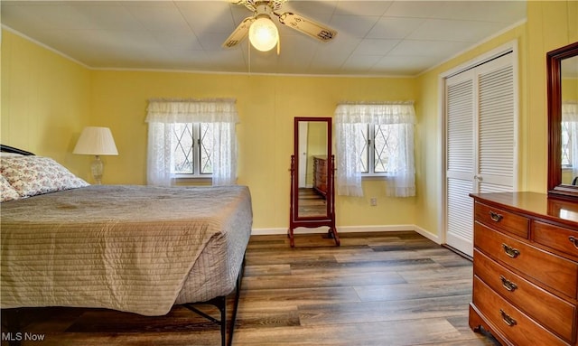 bedroom with crown molding, ceiling fan, a closet, and dark wood-type flooring