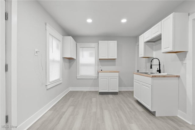 kitchen featuring sink, white cabinets, and light hardwood / wood-style flooring