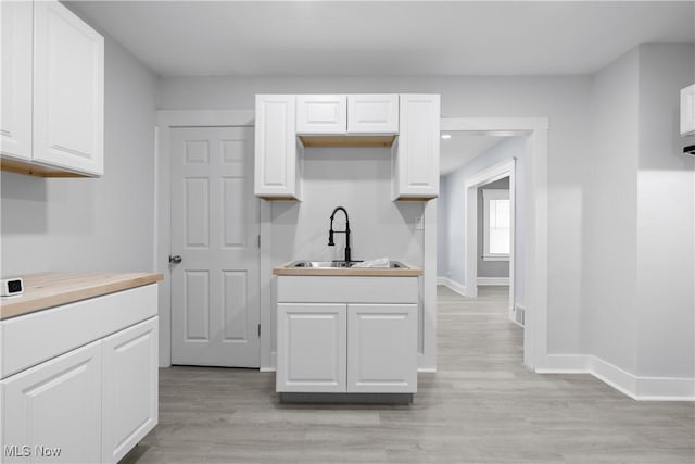 kitchen featuring white cabinetry, sink, and light hardwood / wood-style flooring