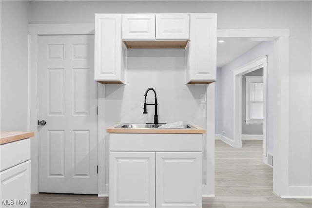 kitchen with sink, white cabinets, and light hardwood / wood-style floors