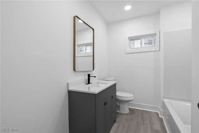 bathroom with vanity, hardwood / wood-style flooring, toilet, and a tub