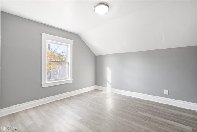 additional living space with wood-type flooring and vaulted ceiling