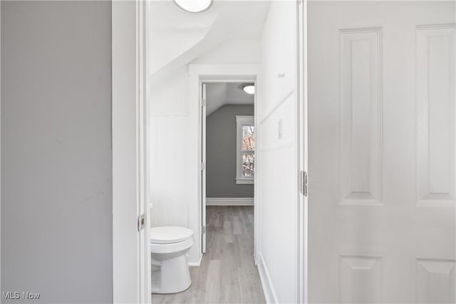 bathroom with hardwood / wood-style flooring, toilet, and vaulted ceiling