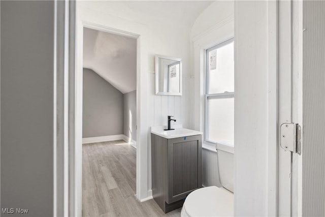 bathroom with vanity, toilet, wood-type flooring, and vaulted ceiling