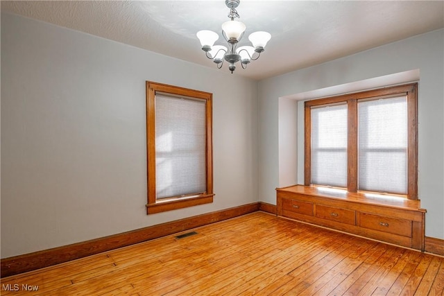 spare room featuring light hardwood / wood-style flooring and an inviting chandelier