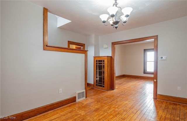 spare room with a chandelier, a textured ceiling, and light wood-type flooring