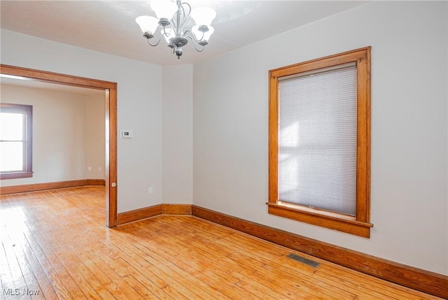 spare room featuring hardwood / wood-style floors and a notable chandelier