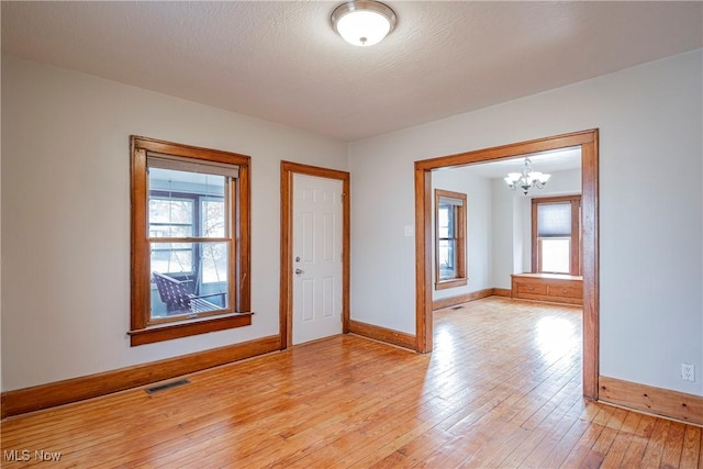 foyer entrance featuring a chandelier, light hardwood / wood-style floors, and plenty of natural light