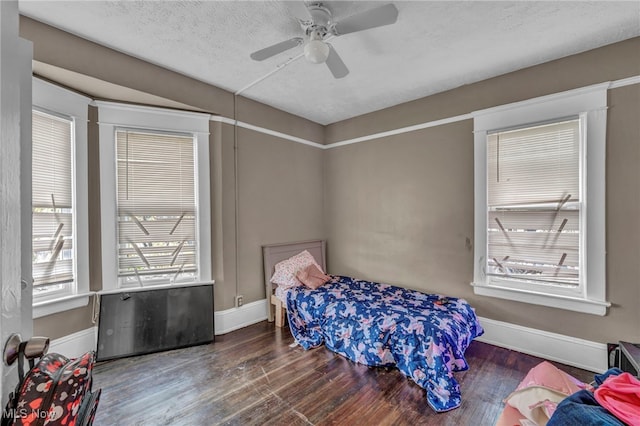 bedroom with a textured ceiling, ceiling fan, and dark wood-type flooring