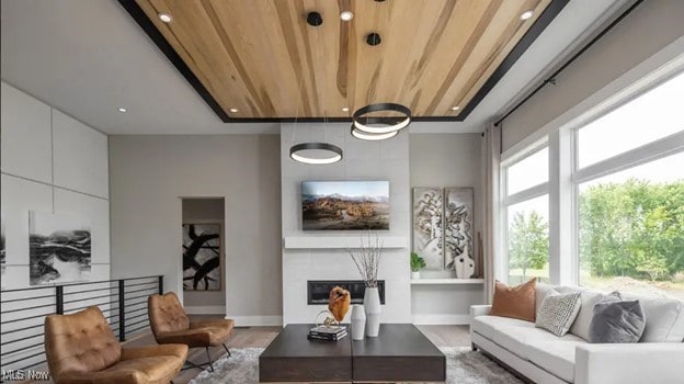 living room featuring hardwood / wood-style floors, wooden ceiling, a fireplace, and a healthy amount of sunlight