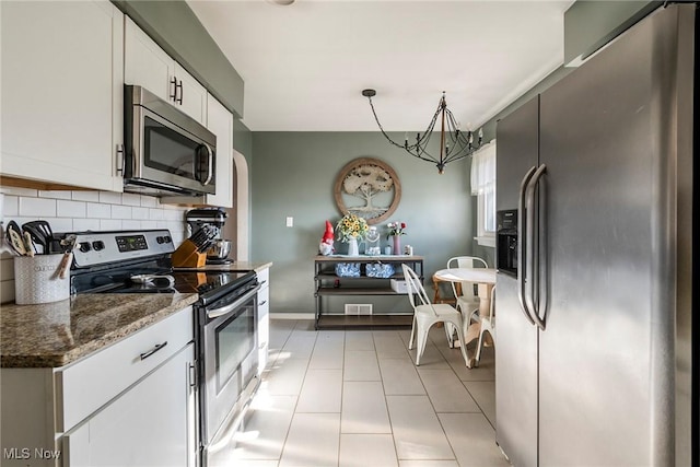 kitchen featuring dark stone countertops, a chandelier, decorative backsplash, white cabinets, and appliances with stainless steel finishes