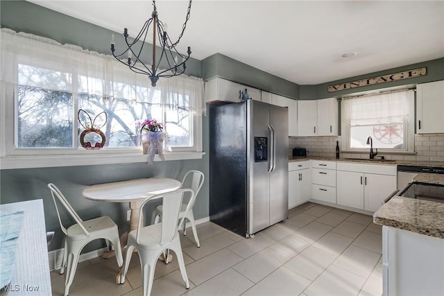 kitchen with backsplash, white cabinets, sink, hanging light fixtures, and appliances with stainless steel finishes