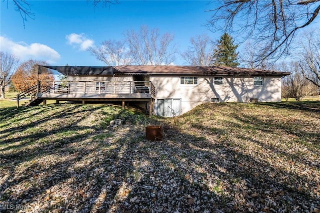 back of property featuring a deck and a lawn