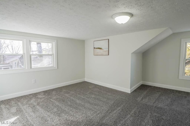 bonus room with a textured ceiling and dark carpet