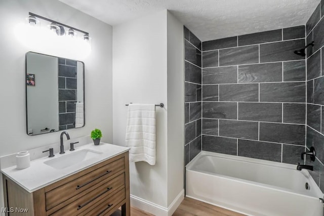 bathroom with hardwood / wood-style flooring, tiled shower / bath combo, a textured ceiling, and vanity