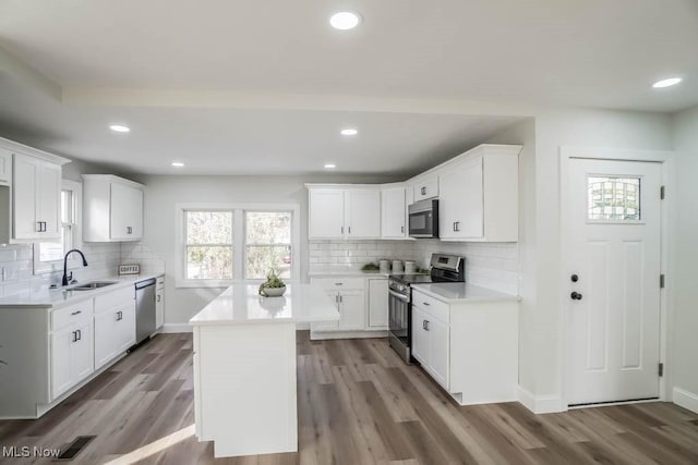 kitchen featuring white cabinetry, light hardwood / wood-style flooring, a kitchen island, and appliances with stainless steel finishes