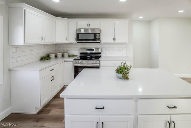 kitchen with tasteful backsplash, white cabinetry, dark hardwood / wood-style floors, and appliances with stainless steel finishes