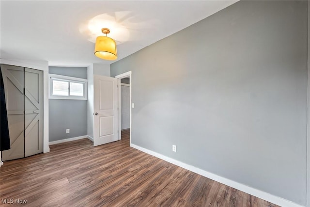 unfurnished bedroom with hardwood / wood-style flooring, a closet, and vaulted ceiling