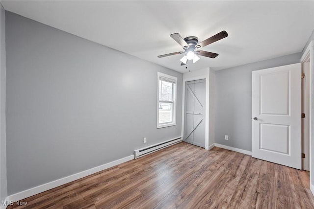 unfurnished bedroom with a closet, light hardwood / wood-style floors, baseboard heating, and ceiling fan