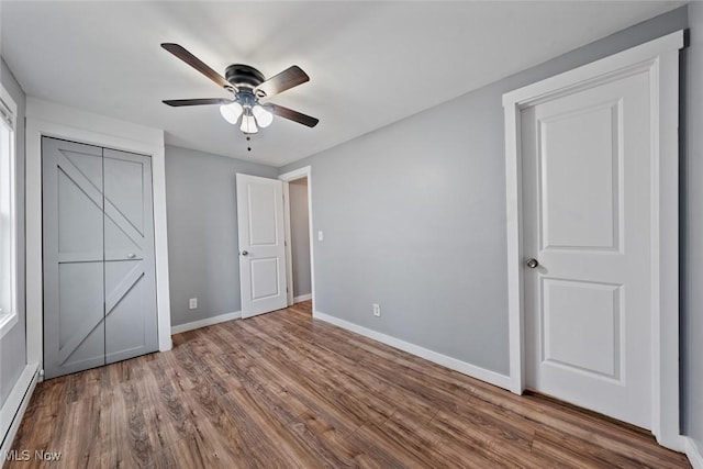 unfurnished bedroom featuring ceiling fan, wood-type flooring, and a baseboard heating unit