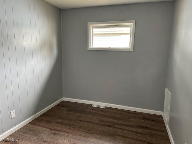 empty room with wooden walls and dark wood-type flooring