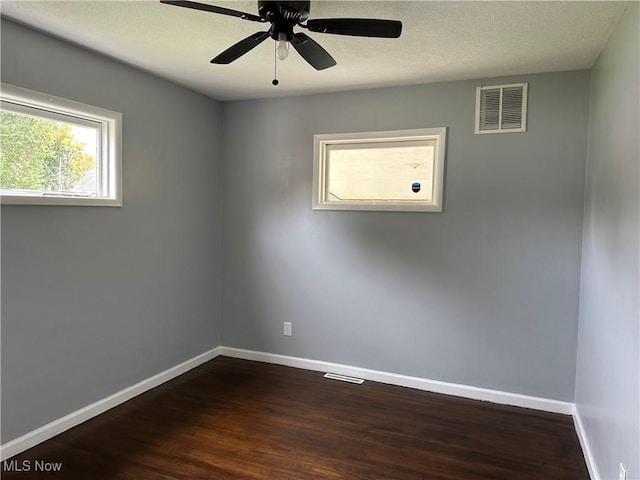 empty room featuring dark hardwood / wood-style floors, ceiling fan, and a textured ceiling